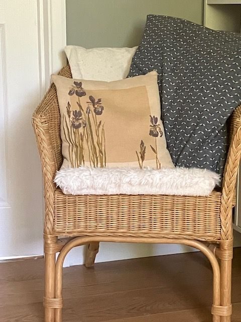 Basket chair with cream base cushion and three loose cushions of cream, grey and printed irises